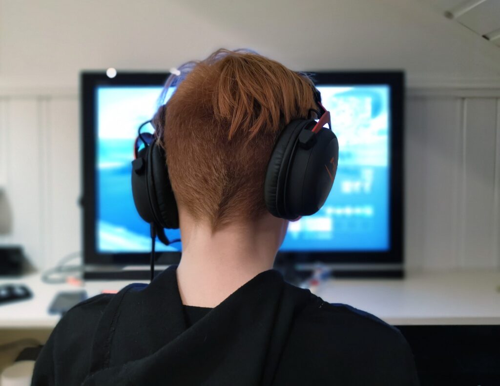 A boy plays video games while wearing Kid's Headphones with a Microphone